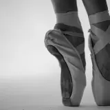 Punte danza classica in primo piano, con nastri incrociati che definiscono la caviglia.