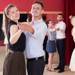 Coppie felici partecipano a corsi di ballo di coppia, imparando passi eleganti in una sala con specchi e tende rosse.