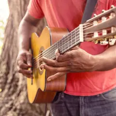 Uomo suona la chitarra acustica, ideale per imparare canzoni in inglese facili da cantare.