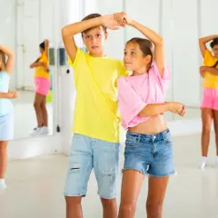 Bambini in una sala da ballo, imparano passi di danza latino americana.