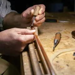 Mani esperte lavorano su un archetto, un'arte che definisce il **liutaio significato**: precisione e passione per creare strumenti musicali.