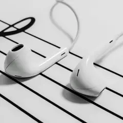 White earbuds resting on a musical staff with a treble clef.