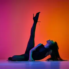 Danza sensuale con tacchi alti, una ballerina si piega all'indietro su uno sfondo sfumato di rosa e arancione.