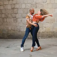 Coppia balla con passione, mostrando la differenza tra salsa e bachata con movimenti fluidi e sensuali.
