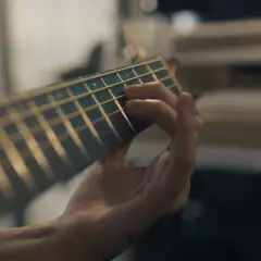 Mano che preme le corde di una chitarra, creando una melodia dal significato profondo.