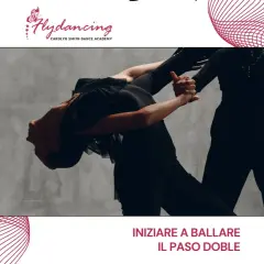 Two dancers in black outfits perform a dramatic Paso Doble pose against a grey backdrop.