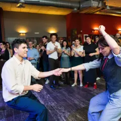 Coppia in movimento durante lezioni di ballo per principianti, con spettatori che osservano.