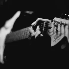 Mani che accarezzano le corde di una chitarra elettrica, creando un blues shuffle intenso e passionale.