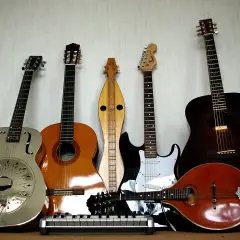 Una collezione di chitarre, tra cui una elettrica, che fa pensare a chi ha inventato la chitarra elettrica.