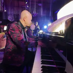 Pianista con giacca fiorata suona la canzone blues più famosa, accompagnato da un altro musicista.