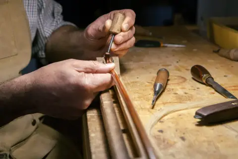 Mani esperte lavorano su un archetto, un'arte che definisce il **liutaio significato**: precisione e passione per creare strumenti musicali.