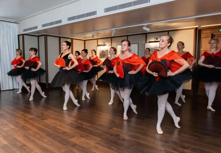 Donne in abiti da balletto nero e rosso, con ventagli, pronte a fare danza.