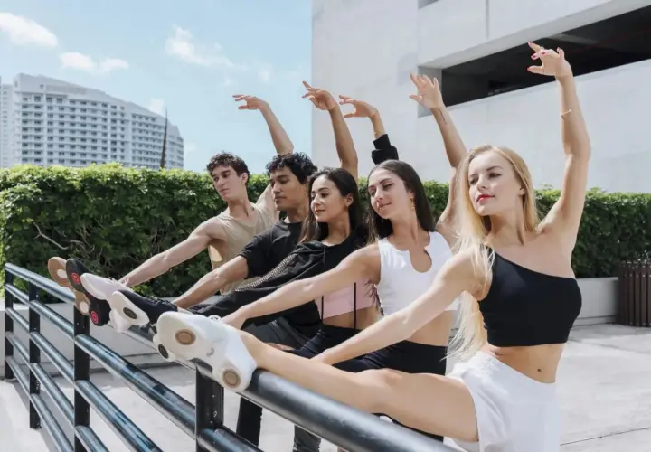 Giovani ballerini si allenano all'aperto, mostrando diversi tipi di balli con grazia.