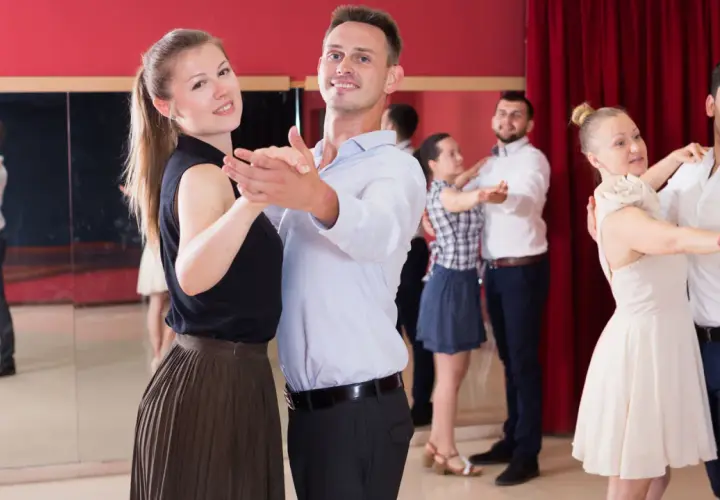 Coppie felici partecipano a corsi di ballo di coppia, imparando passi eleganti in una sala con specchi e tende rosse.
