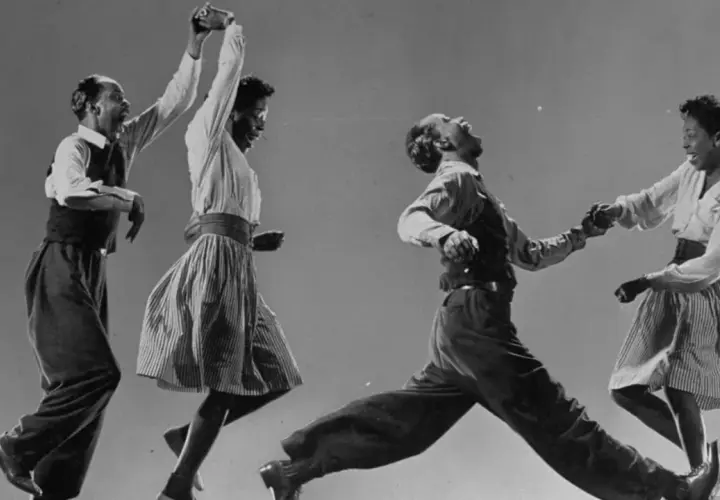Coppia balla il lindy hop con energia e gioia, in un'esplosione di movimento e ritmo.