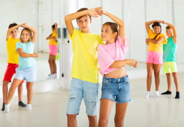 Bambini in una sala da ballo, imparano passi di danza latino americana.