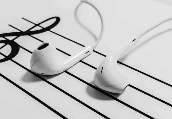 White earbuds resting on a musical staff with a treble clef.