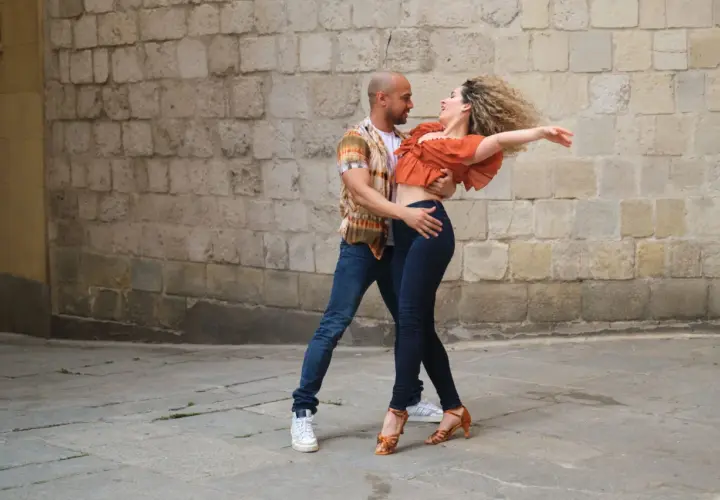 Coppia balla con passione, mostrando la differenza tra salsa e bachata con movimenti fluidi e sensuali.