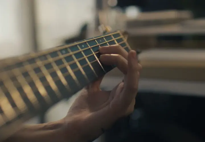 Mano che preme le corde di una chitarra, creando una melodia dal significato profondo.
