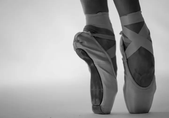 Punte danza classica in primo piano, con nastri incrociati che definiscono la caviglia.