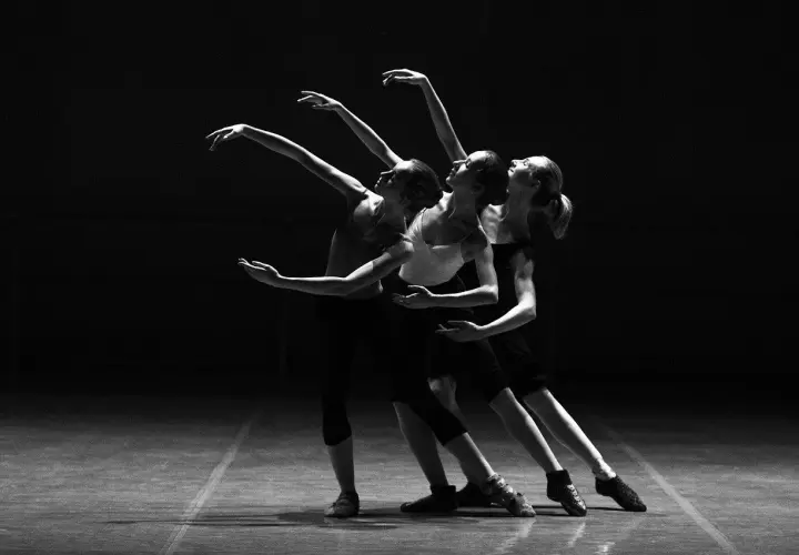 Tre ballerine in posa aggraziata durante lezioni di danza, con le braccia tese e i corpi in movimento.