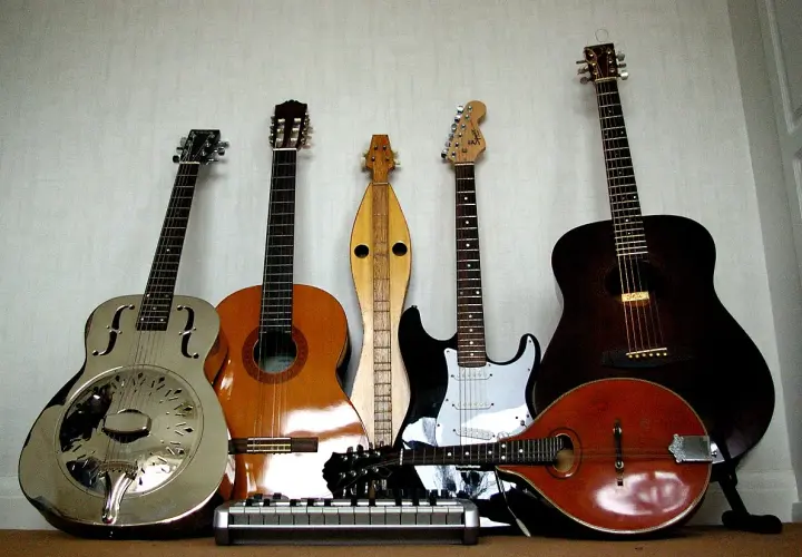 Una collezione di chitarre, tra cui una elettrica, che fa pensare a chi ha inventato la chitarra elettrica.