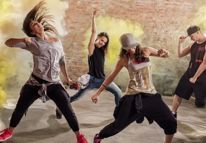 Un gruppo di ballerini energici in un ambiente urbano, circondati da fumo giallo. Un esempio di video dance cos'è: pura espressione e movimento.