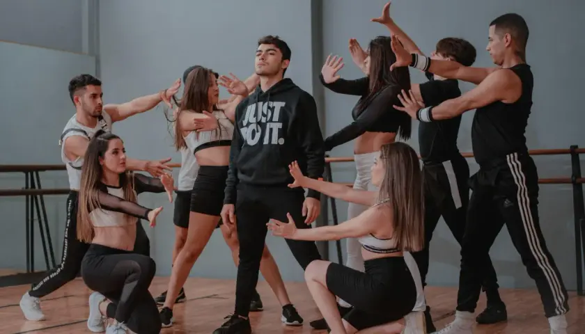 Un gruppo di giovani ballerini in un ipop ballo, con un ragazzo al centro che indossa una felpa "Just Do It".