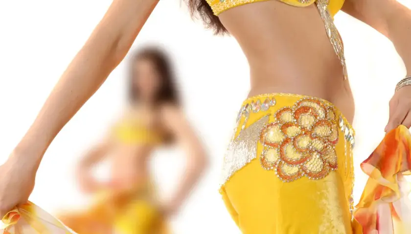 Dettaglio di una ballerina che esegue una danza del ventre, con abito giallo decorato e velo colorato.