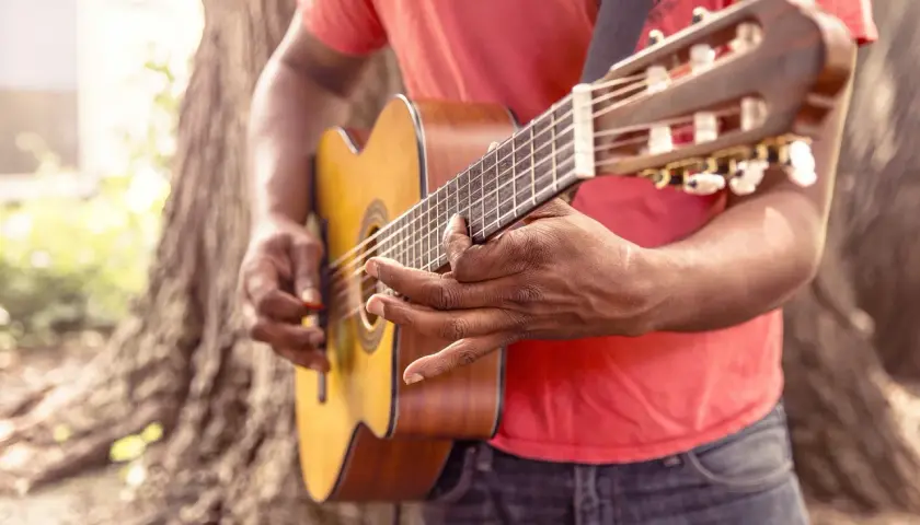 Uomo suona la chitarra acustica, ideale per imparare canzoni in inglese facili da cantare.