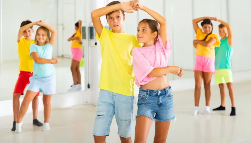 Bambini in una sala da ballo, imparano passi di danza latino americana.