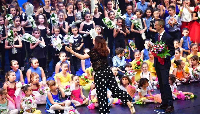 Giovani ballerini festeggiano sul palco dopo un'esibizione di rumba ballo latino americano, ricevendo fiori e applausi.