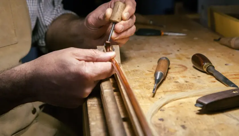 Mani esperte lavorano su un archetto, un'arte che definisce il **liutaio significato**: precisione e passione per creare strumenti musicali.