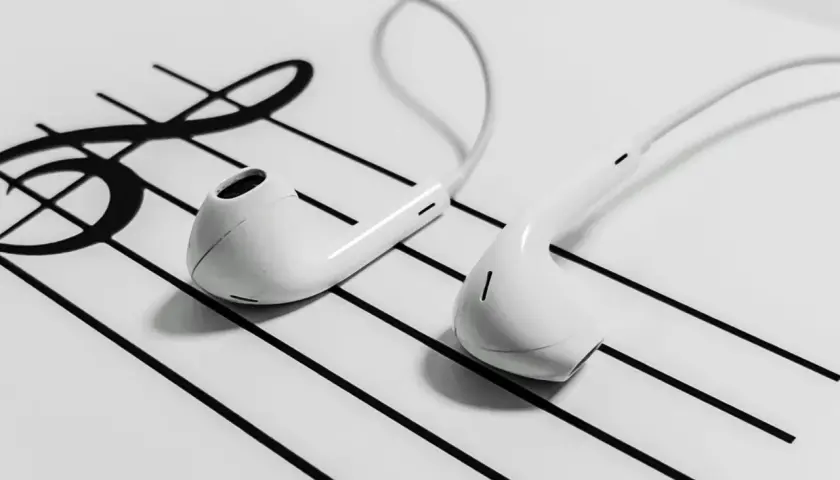 White earbuds resting on a musical staff with a treble clef.