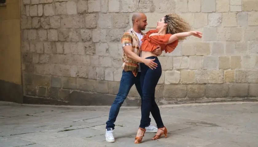 Coppia balla con passione, mostrando la differenza tra salsa e bachata con movimenti fluidi e sensuali.