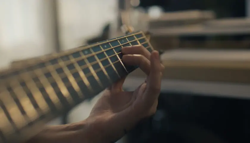 Mano che preme le corde di una chitarra, creando una melodia dal significato profondo.