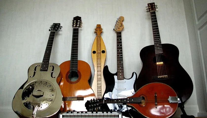 Una collezione di chitarre, tra cui una elettrica, che fa pensare a chi ha inventato la chitarra elettrica.