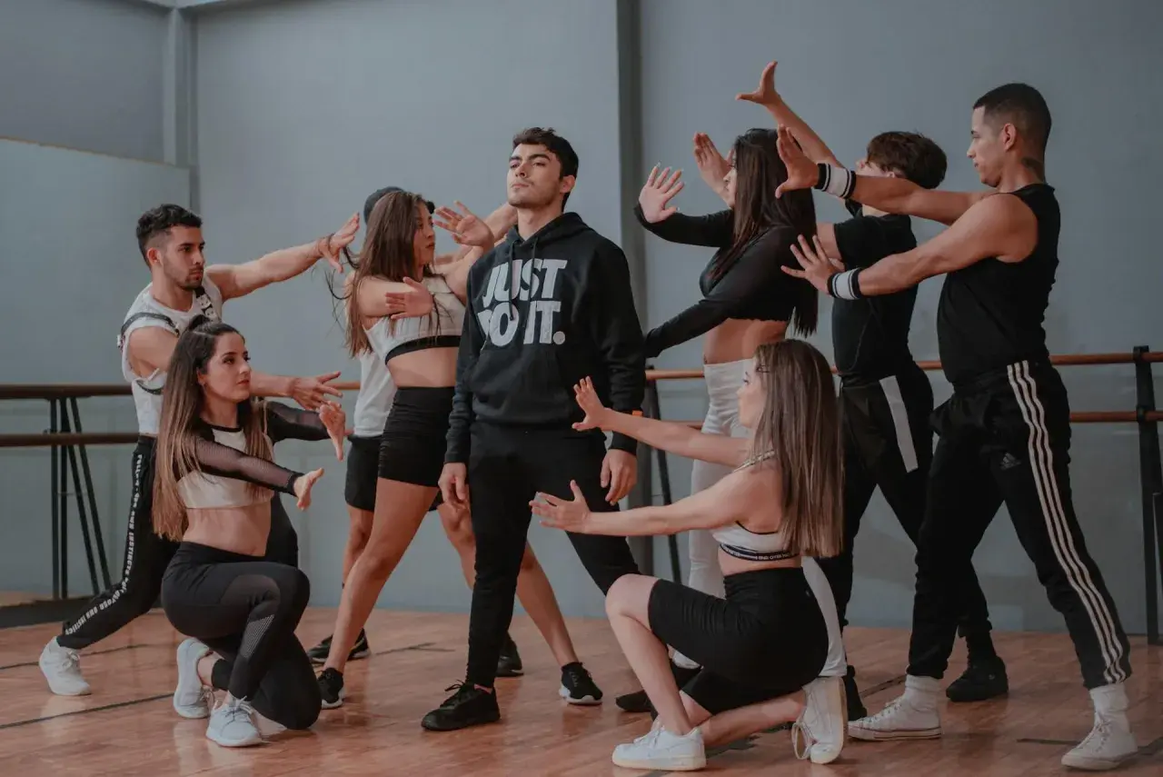 Un gruppo di giovani ballerini in un ipop ballo, con un ragazzo al centro che indossa una felpa "Just Do It".