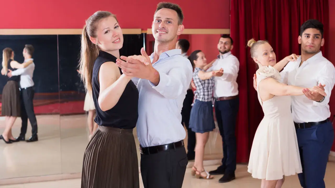 Coppie felici partecipano a corsi di ballo di coppia, imparando passi eleganti in una sala con specchi e tende rosse.