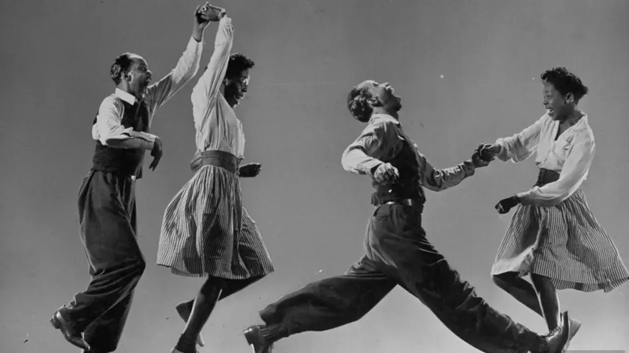 Coppia balla il lindy hop con energia e gioia, in un'esplosione di movimento e ritmo.