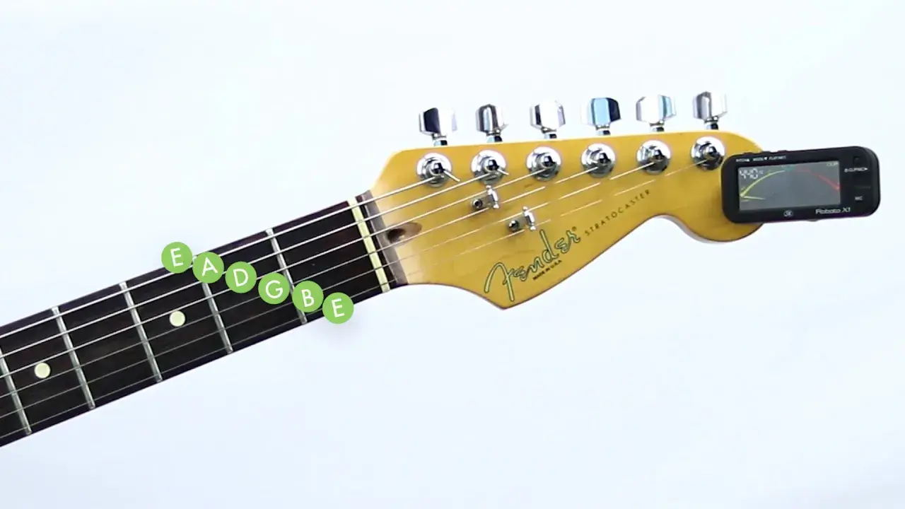 Accordatura chitarra: le note E, A, D, G, B, E evidenziate sul manico, con accordatore elettronico agganciato alla paletta.