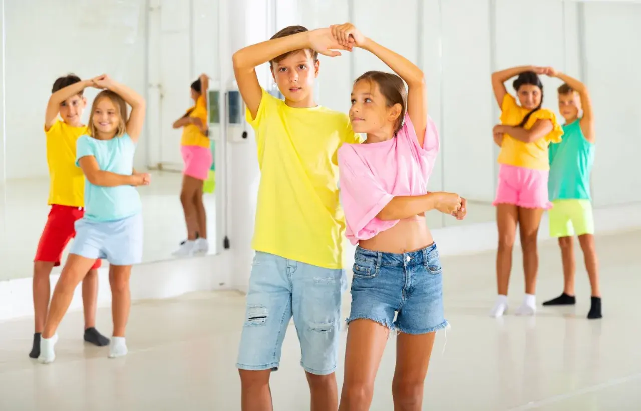 Bambini in una sala da ballo, imparano passi di danza latino americana.