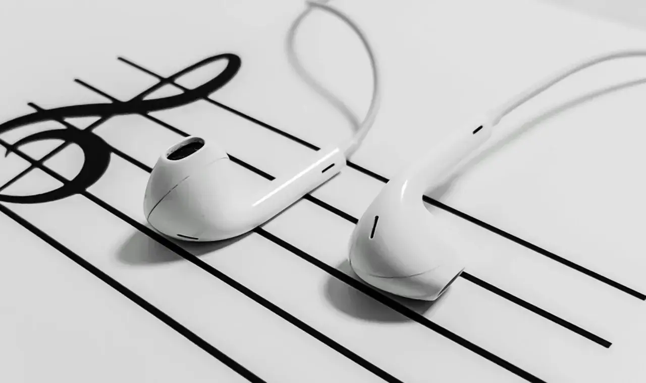 White earbuds resting on a musical staff with a treble clef.