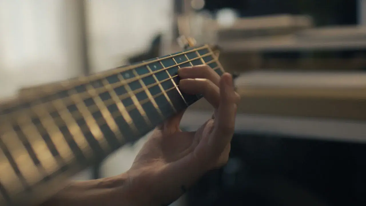 Mano che preme le corde di una chitarra, creando una melodia dal significato profondo.