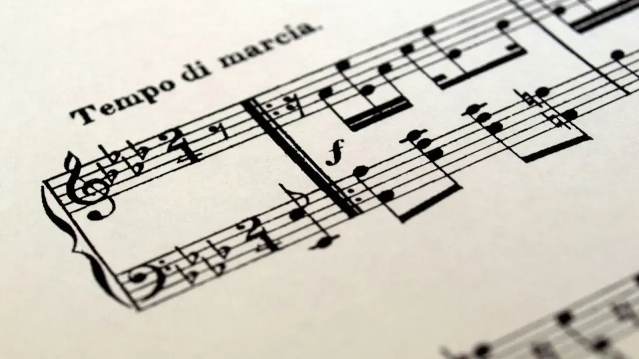 Spartito musicale con indicazione "Tempo di marcia". Le note suggeriscono un ritmo deciso, un tempo tagliato per una marcia solenne.