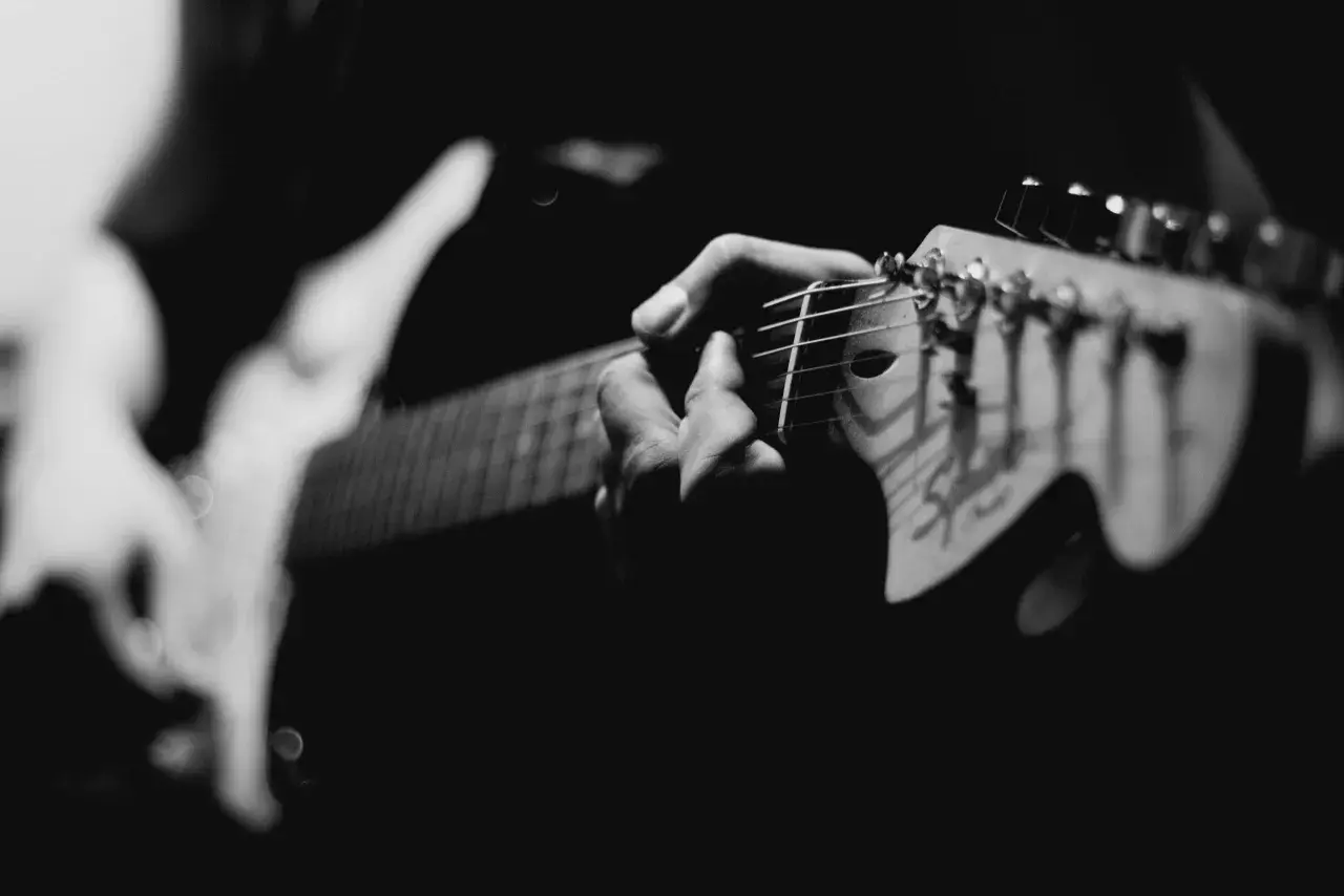 Mani che accarezzano le corde di una chitarra elettrica, creando un blues shuffle intenso e passionale.