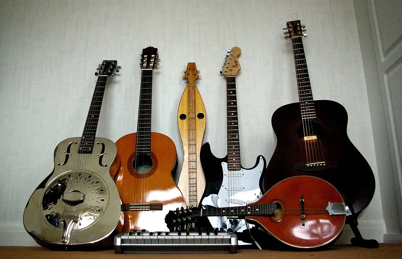 Una collezione di chitarre, tra cui una elettrica, che fa pensare a chi ha inventato la chitarra elettrica.