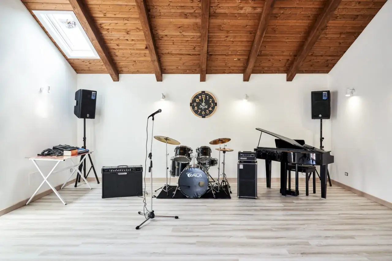 Sala prove con pianoforte, batteria, microfono e amplificatori, pronta per creare canzoni danza moderna.