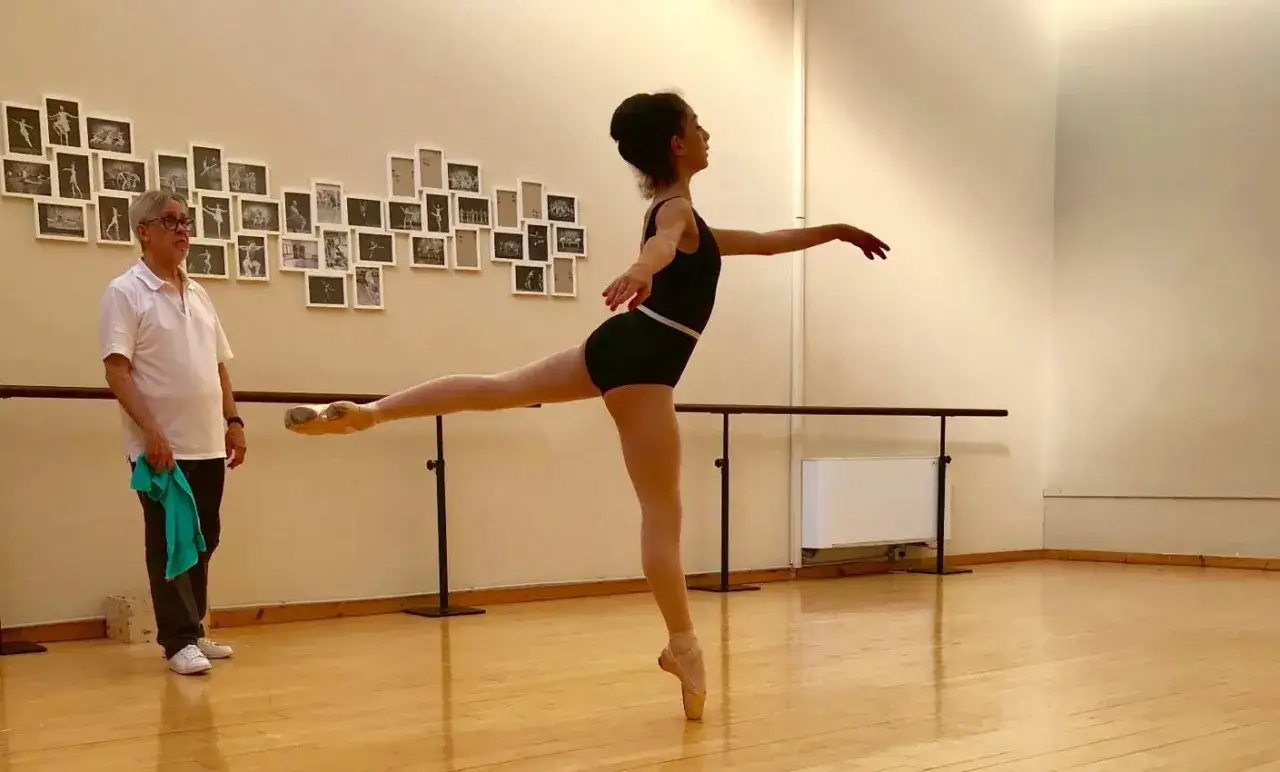 Un maestro osserva una ballerina in posa, un'immagine che cattura l'essenza di cos'&egrave; la danza classica: disciplina, grazia e dedizione.
