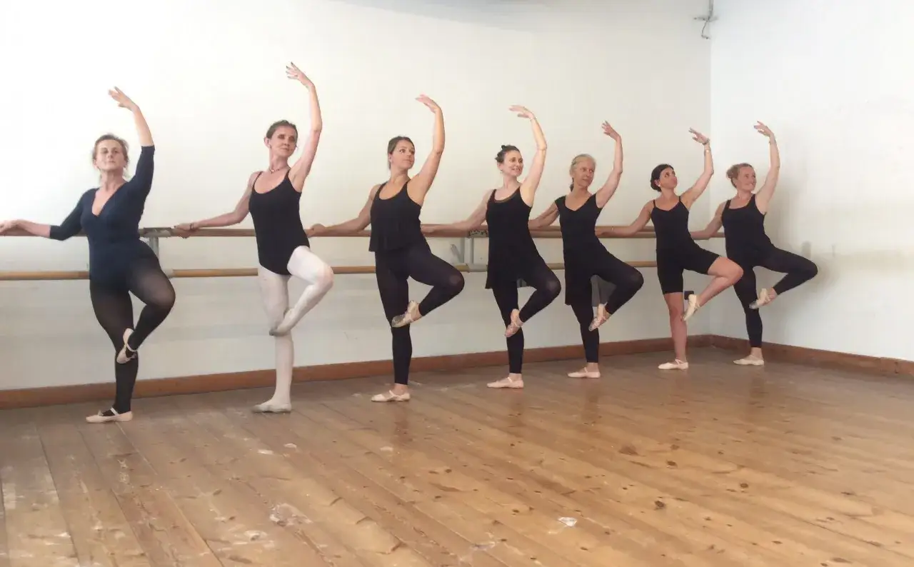 Un gruppo di donne partecipa a lezioni di danza, eseguendo posizioni di balletto con grazia.